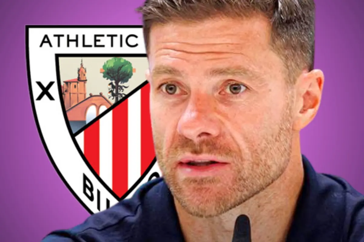 Hombre de cabello corto y barba recortada en primer plano con el escudo del Athletic Club de Bilbao de fondo sobre un fondo morado
