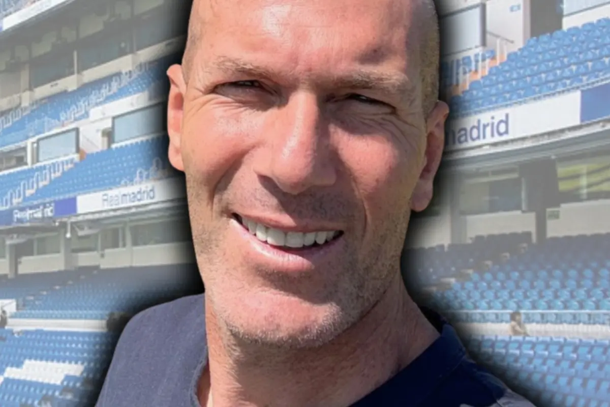 Hombre calvo sonriendo con gradas azules de un estadio de fondo