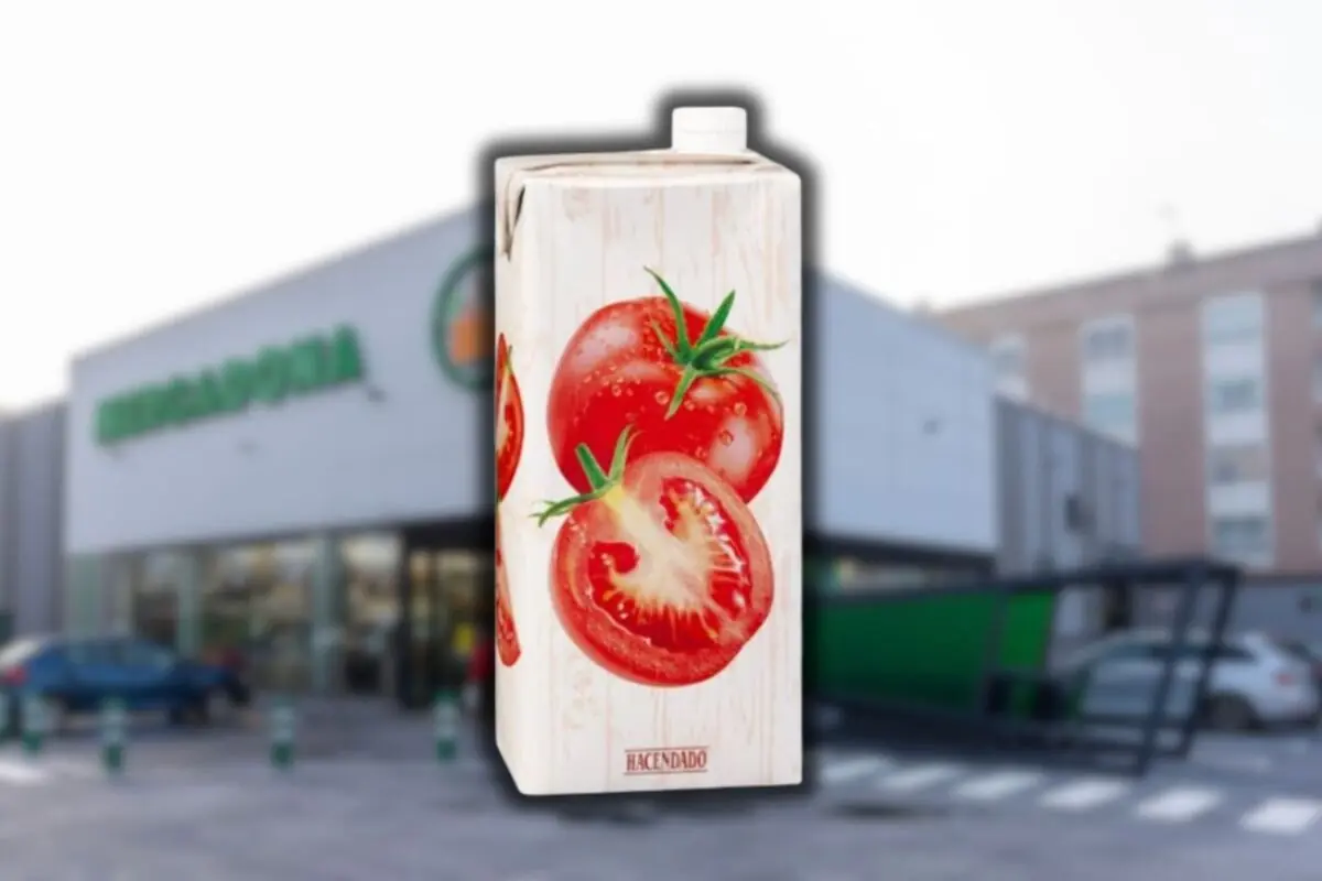 Envase de tomate triturado de la marca Hacendado en primer plano frente a un supermercado Mercadona desenfocado