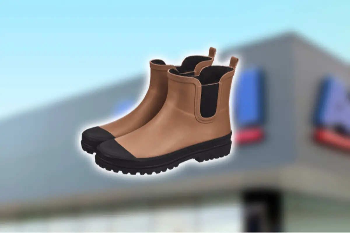 Botas de lluvia color café con suela y puntera negras sobre fondo desenfocado de tienda Botas de lluvia color café con suela y puntera negras sobre fondo desenfocado de tienda