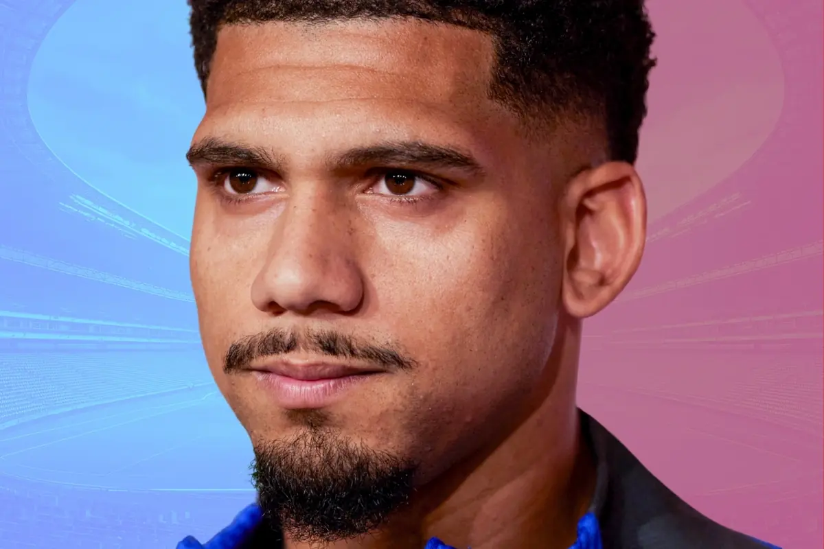 Retrat d’un home jove amb barba curta i expressió seriosa sobre un fons degradat blau i rosa