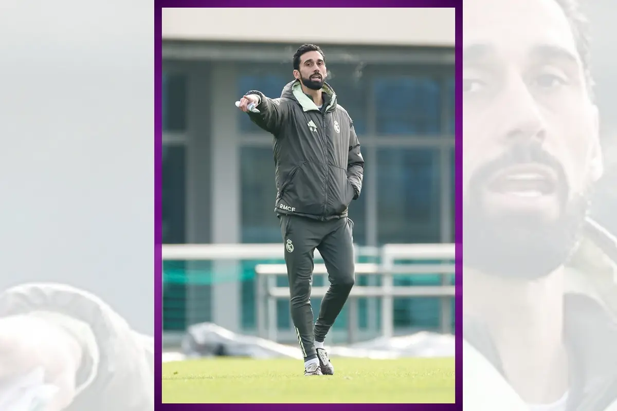 Entrenador de fútbol con chándal oscuro del Real Madrid dando indicaciones en un campo de entrenamiento