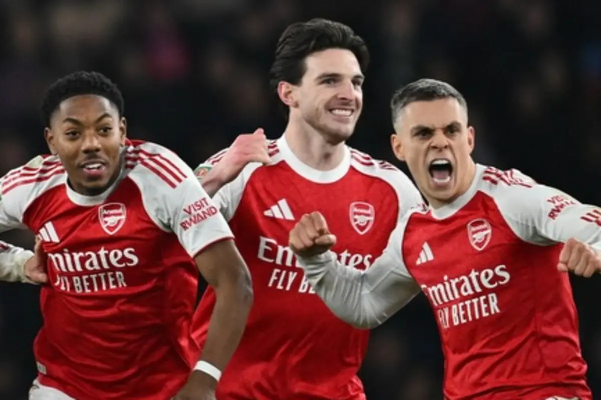 Tres futbolistas del Arsenal con uniforme rojo celebran efusivamente en el campo tras una jugada exitosa