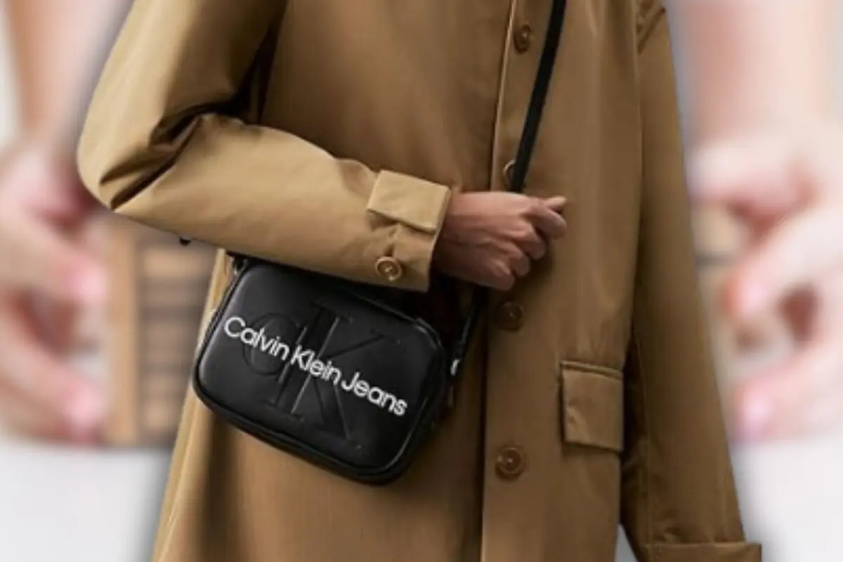 Persona amb gavardina beix portant una bossa negra creuada Calvin Klein Jeans