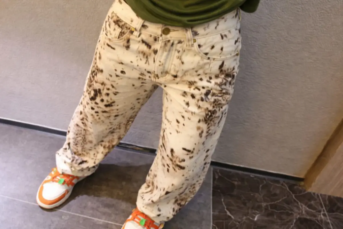 Pantalones anchos color crema con manchas marrones tipo salpicaduras combinados con tenis blancos naranjas y verdes