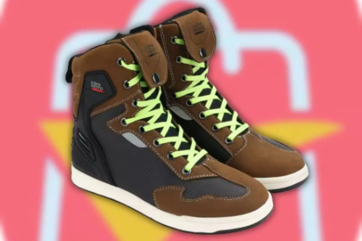 Botas deportivas marrones y negras con cordones verdes sobre fondo rosa desenfocado