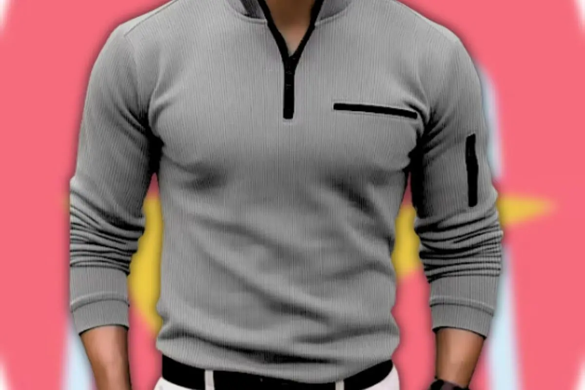 Hombre vistiendo suéter gris ajustado con cremallera corta frontal y bolsillos negros sobre fondo rosa