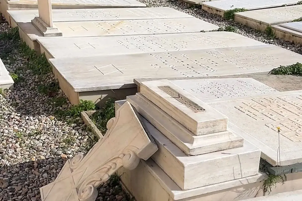 Lápidas de mármol en un cementerio con una columna rota caída sobre una de las tumbas