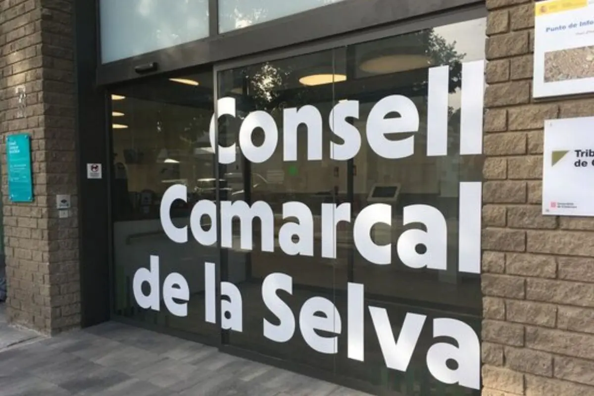 Entrada envidrada de l’edifici del Consell Comarcal de la Selva amb el seu nom en grans lletres blanques sobre la porta corredissa