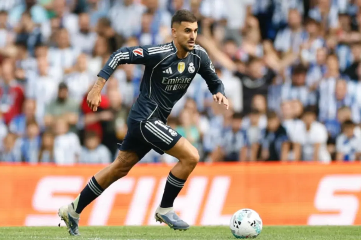 Futbolista del Reial Madrid amb uniforme fosc corrent cap a la pilota durant un partit amb el públic desenfocat de fons Futbolista del Reial Madrid amb uniforme fosc corrent cap a la pilota durant un partit amb el públic desenfocat de fons