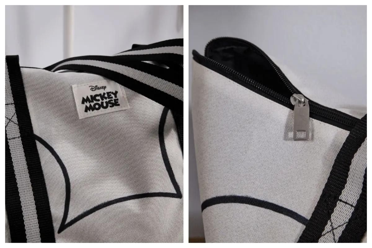 Detalle de bolso de tela gris con diseño de Mickey Mouse de Aldi mostrando etiqueta de la marca y cierre de cremallera negro.