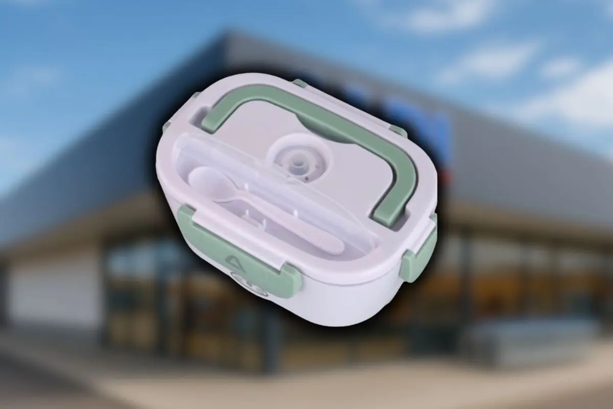Lonchera eléctrica blanca con detalles verdes y compartimento para cubiertos sobre fondo de una tienda Aldi desenfocada.