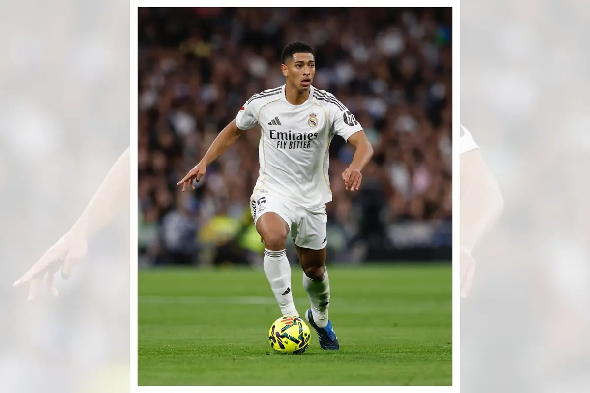 Futbolista del Real Madrid con uniforme blanco conduciendo el balón durante un partido en un estadio lleno Futbolista del Real Madrid con uniforme blanco conduciendo el balón durante un partido en un estadio lleno