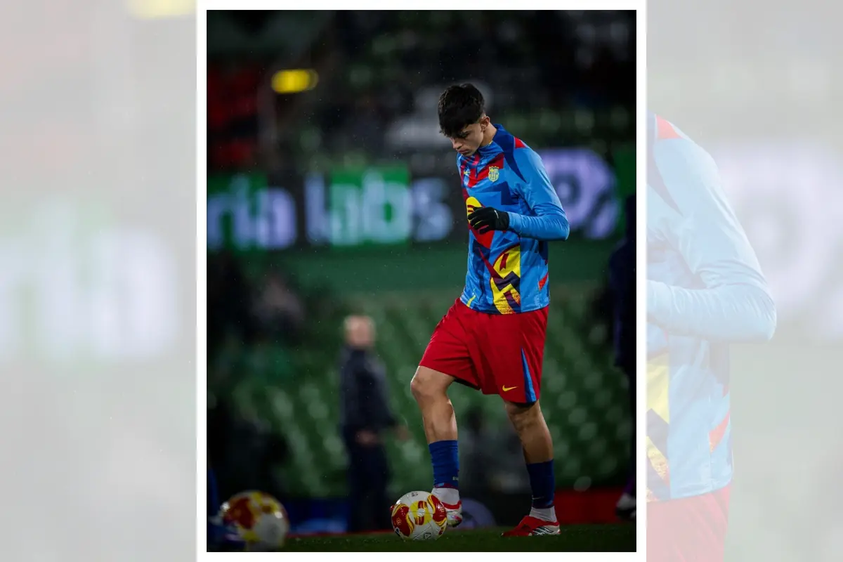 Futbolista joven con uniforme de calentamiento colorido controla un balón sobre el césped de un estadio vacío durante el entrenamiento antes de un partido