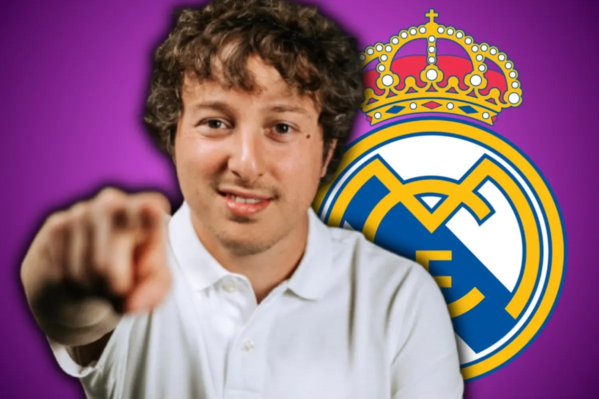 Hombre joven con camiseta blanca señalando a la cámara frente al escudo del Real Madrid sobre fondo morado