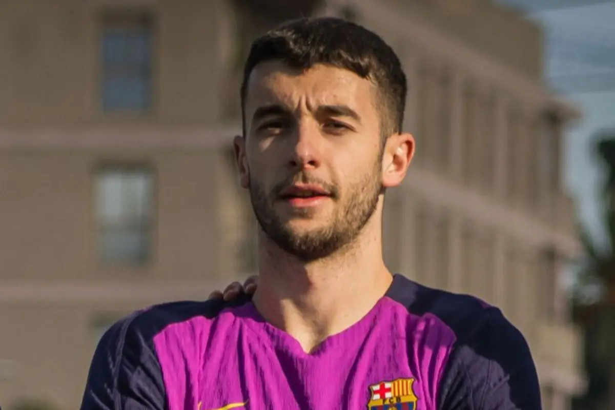 Grupo de jóvenes futbolistas del FC Barcelona posando sonrientes en el campo de entrenamiento con petos azules y uniforme morado y azul