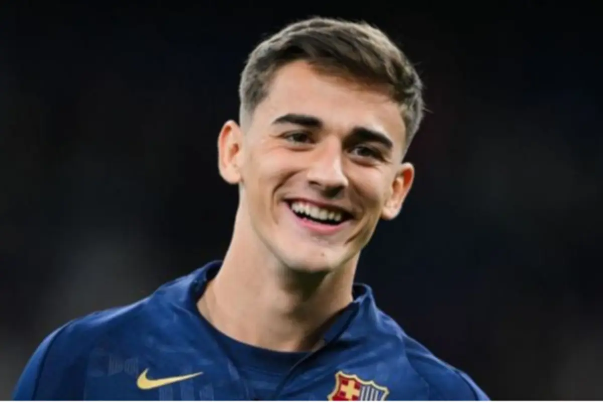 Jove futbolista somrient amb samarreta blava del FC Barcelona sobre fons fosc