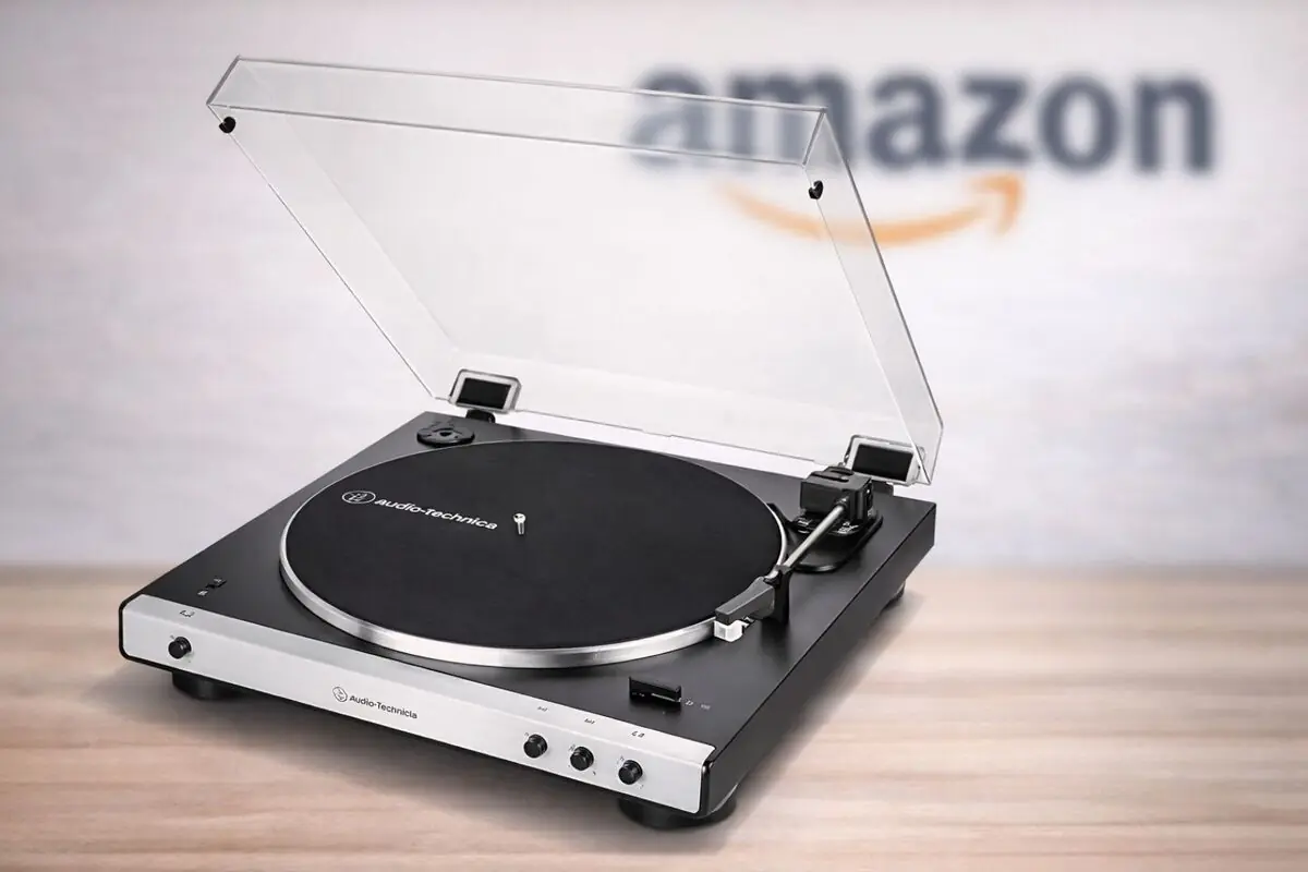 Tocadiscos Audio Technica negro con tapa transparente abierto sobre mesa de madera con el logo de Amazon desenfocado al fondo