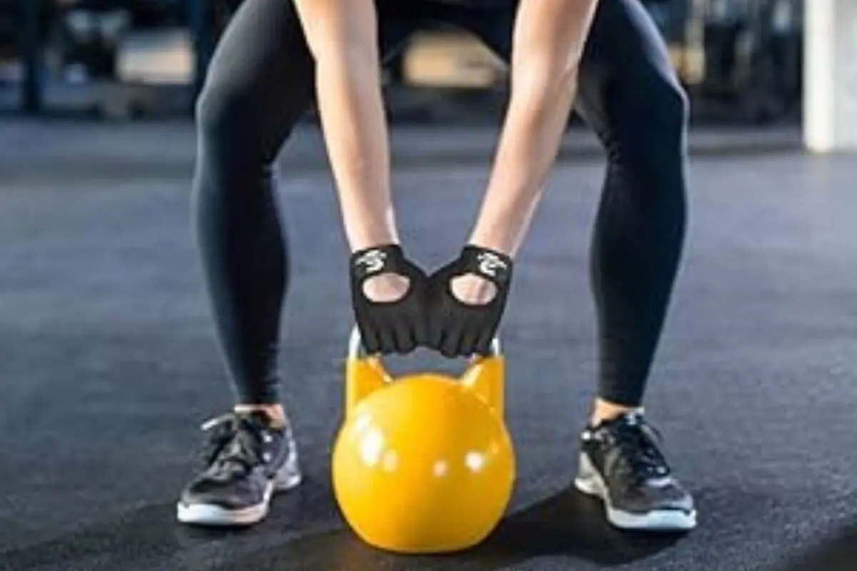 Persona haciendo ejercicio con pesa rusa amarilla en un gimnasio Persona haciendo ejercicio con pesa rusa amarilla en un gimnasio