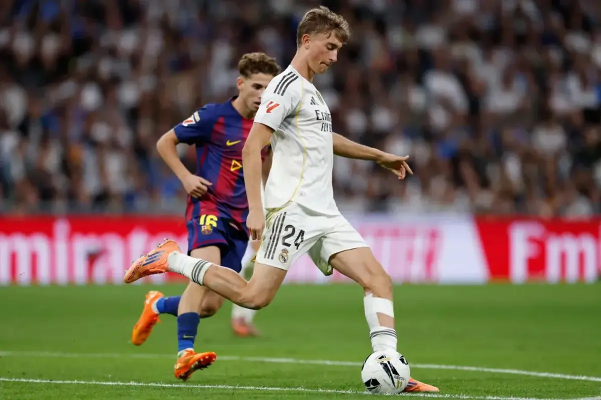 Futbolista del Reial Madrid controla la pilota mentre un jugador del Barcelona el persegueix en un partit amb l’estadi ple