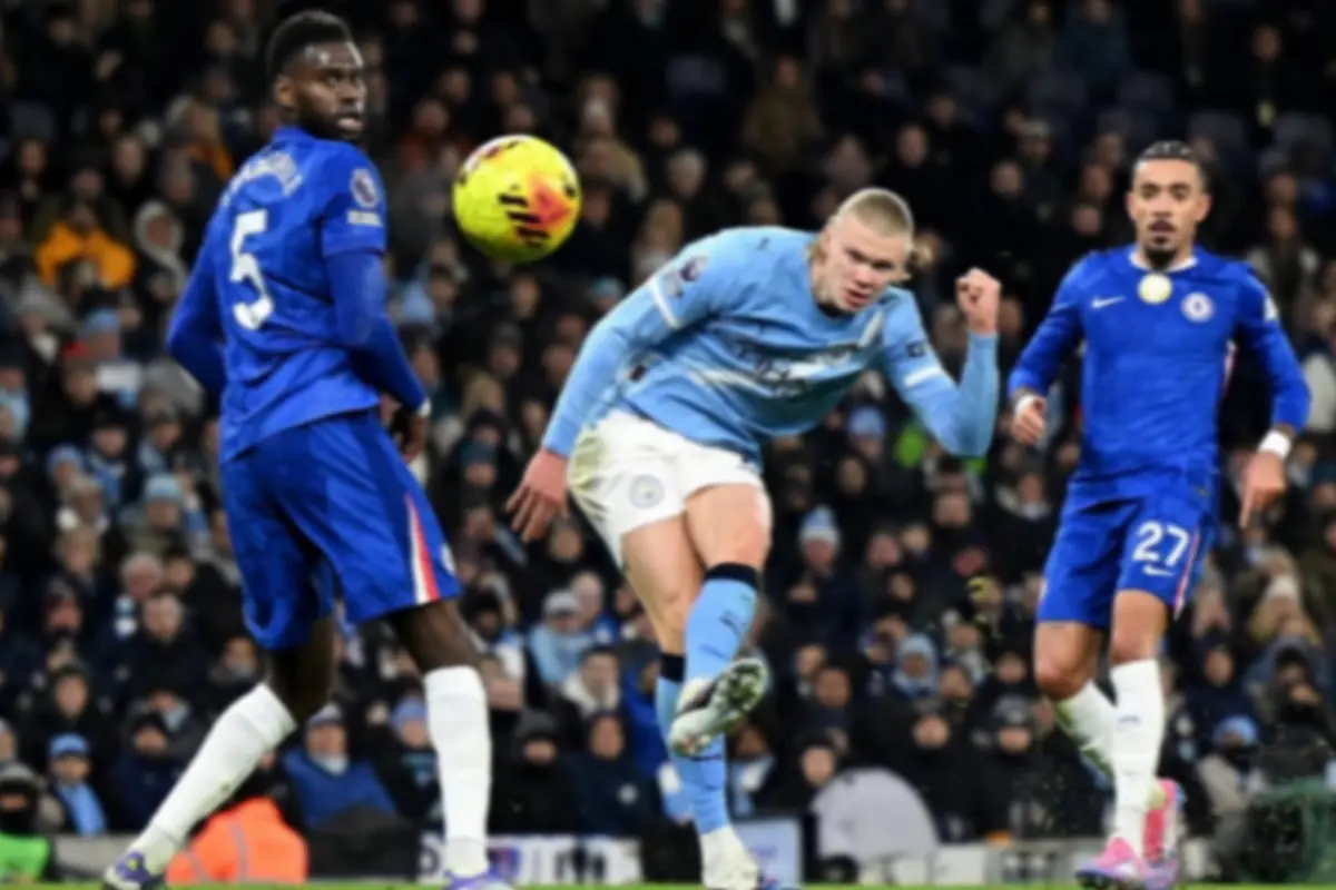 Futbolista del Manchester City remata el balón rodeado de dos defensores del Chelsea en un estadio lleno de aficionados