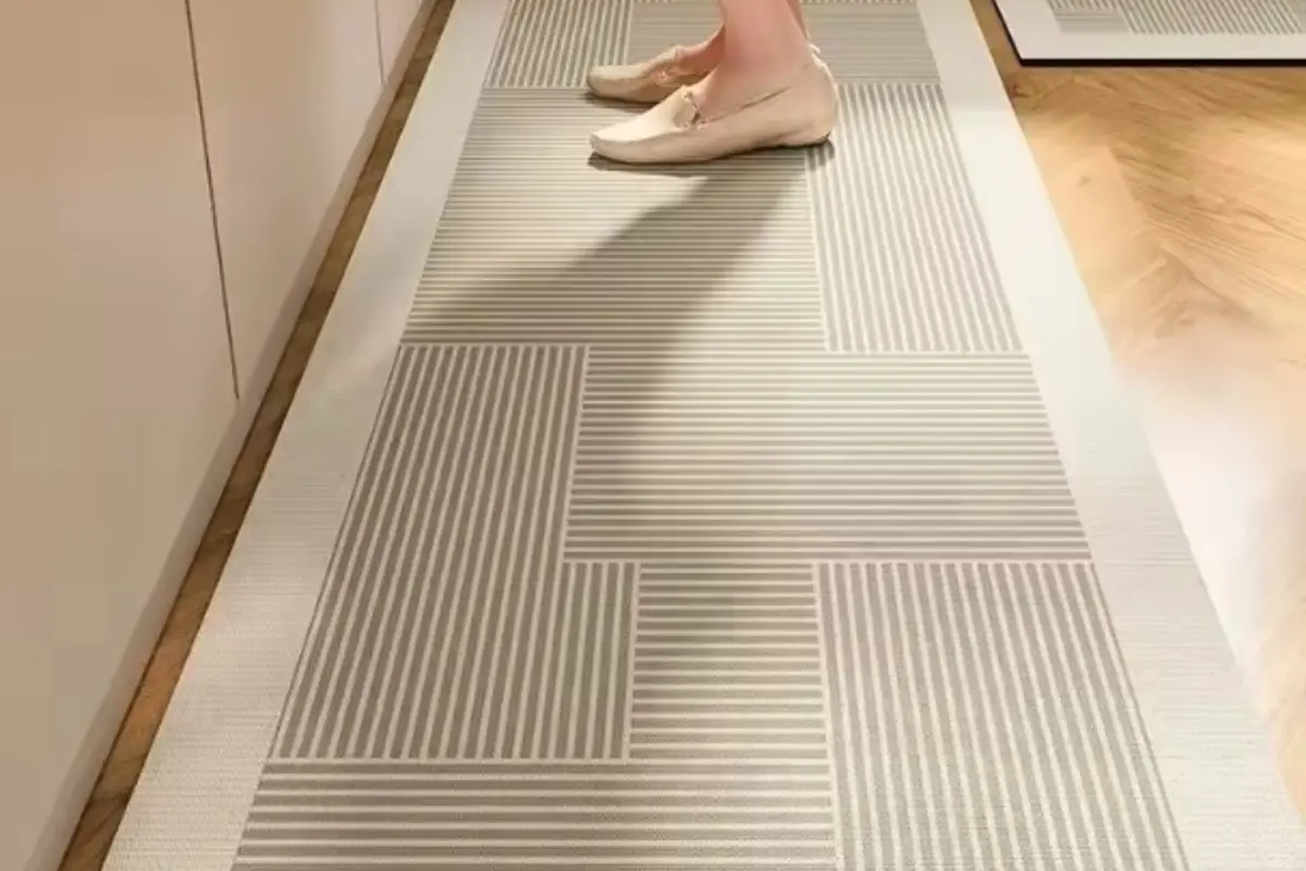 Persona de pie sobre una alfombra rectangular de diseño geométrico en tonos beige colocada en el suelo de una cocina