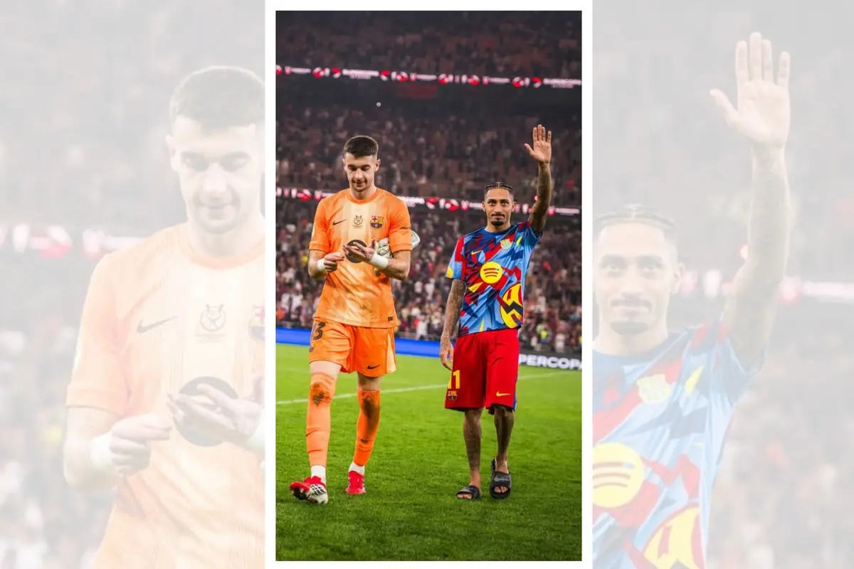 Dos futbolistes del Barcelona caminen sobre la gespa després d’un partit, un amb uniforme de porter taronja mirant un objecte a les mans i l’altre amb samarreta blava multicolor i pantalons vermells saludant l’afició amb la graderia plena al fons Dos futbolistes del Barcelona caminen sobre la gespa després d’un partit, un amb uniforme de porter taronja mirant un objecte a les mans i l’altre amb samarreta blava multicolor i pantalons vermells saludant l’afició amb la graderia plena al fons