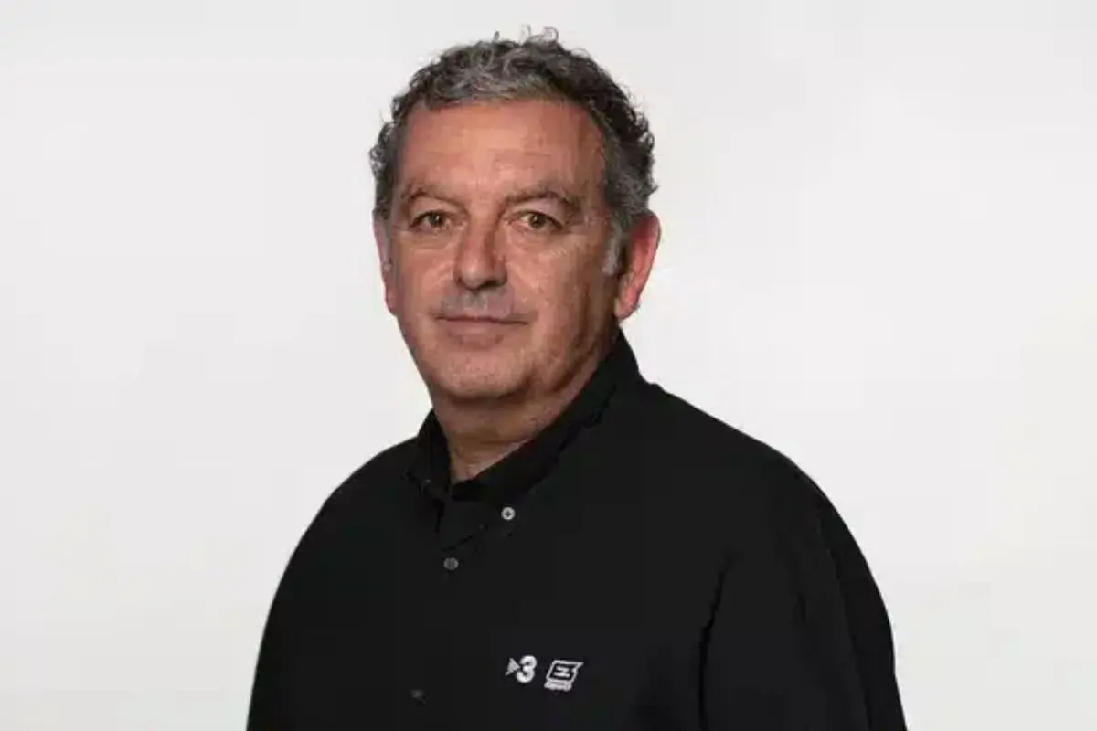 Retrato de un hombre de mediana edad con camisa negra sobre fondo blanco mirando a la cámara