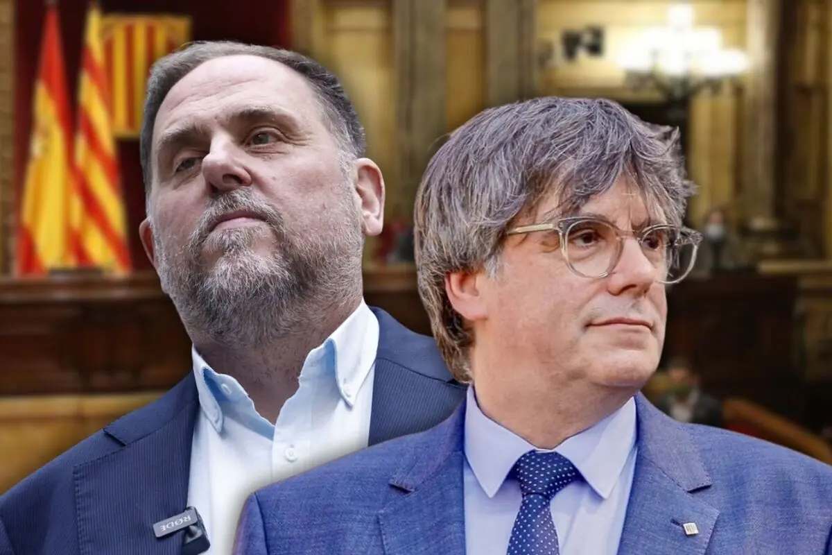 Dos homes amb vestit en primer pla dins d’un parlament amb banderes d’Espanya i de Catalunya al fons