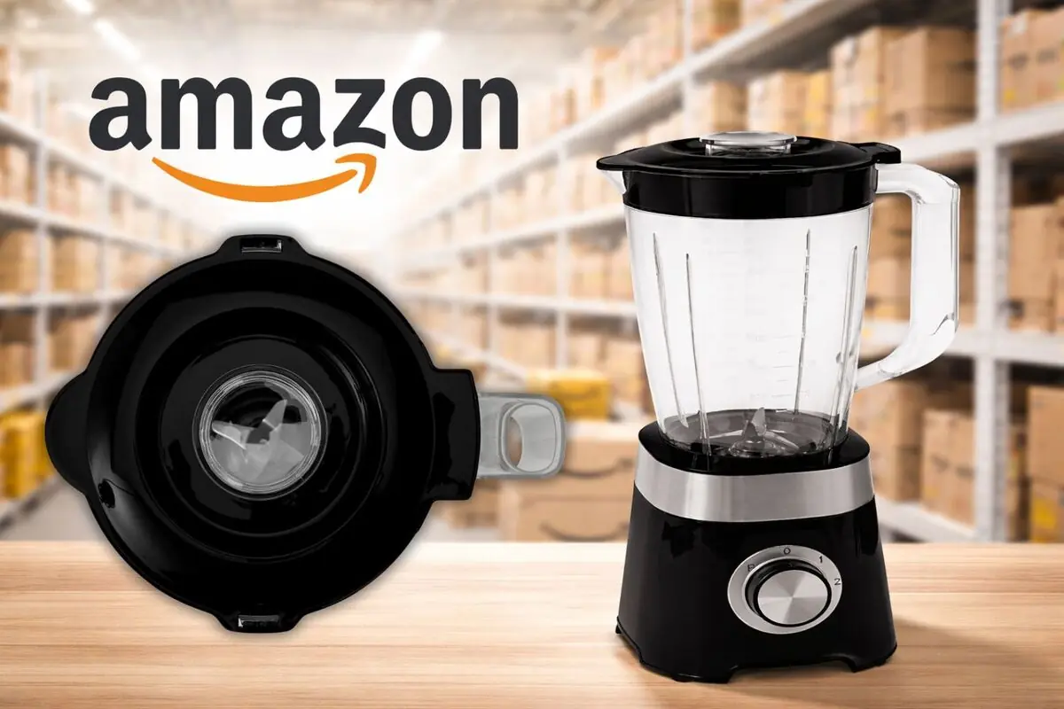Licuadora eléctrica negra sobre mesa de madera con vista superior de la tapa y logo de Amazon al fondo en un almacén con estanterías de cajas