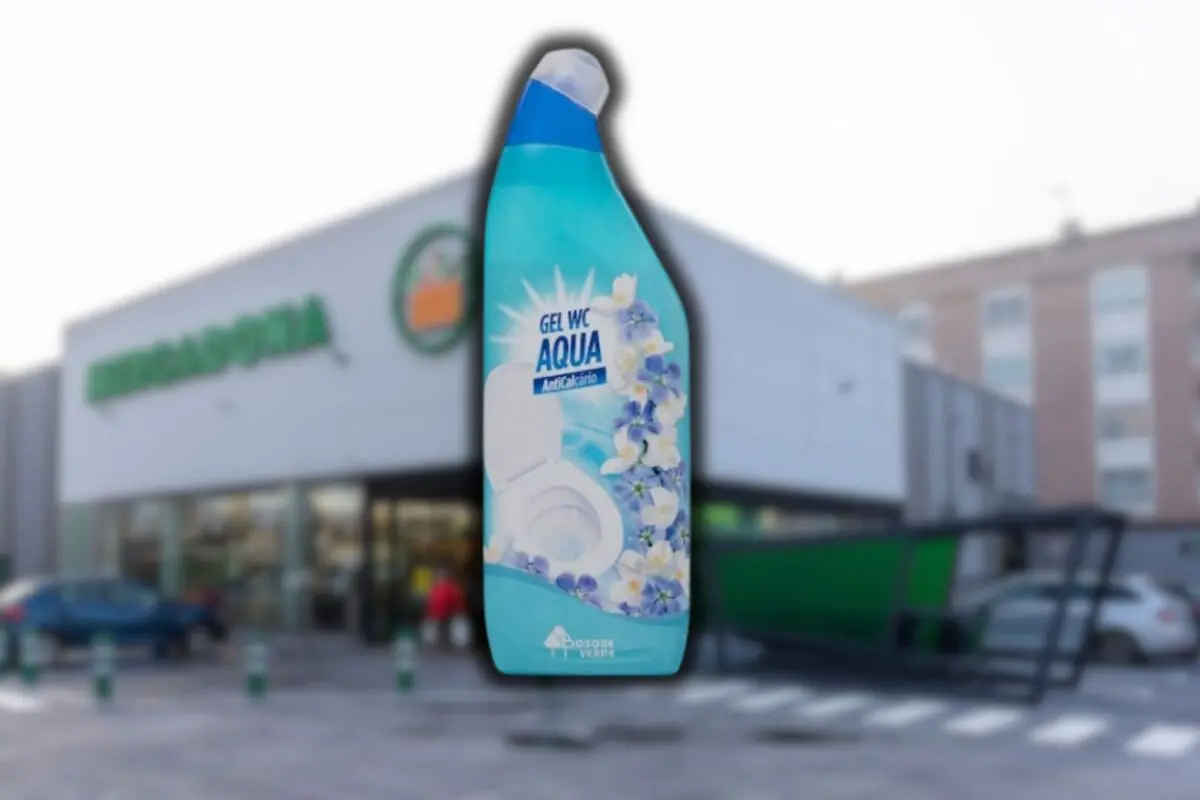Botella de gel limpiador para WC de color azul con flores en la etiqueta frente a la fachada de un supermercado Mercadona desenfocada