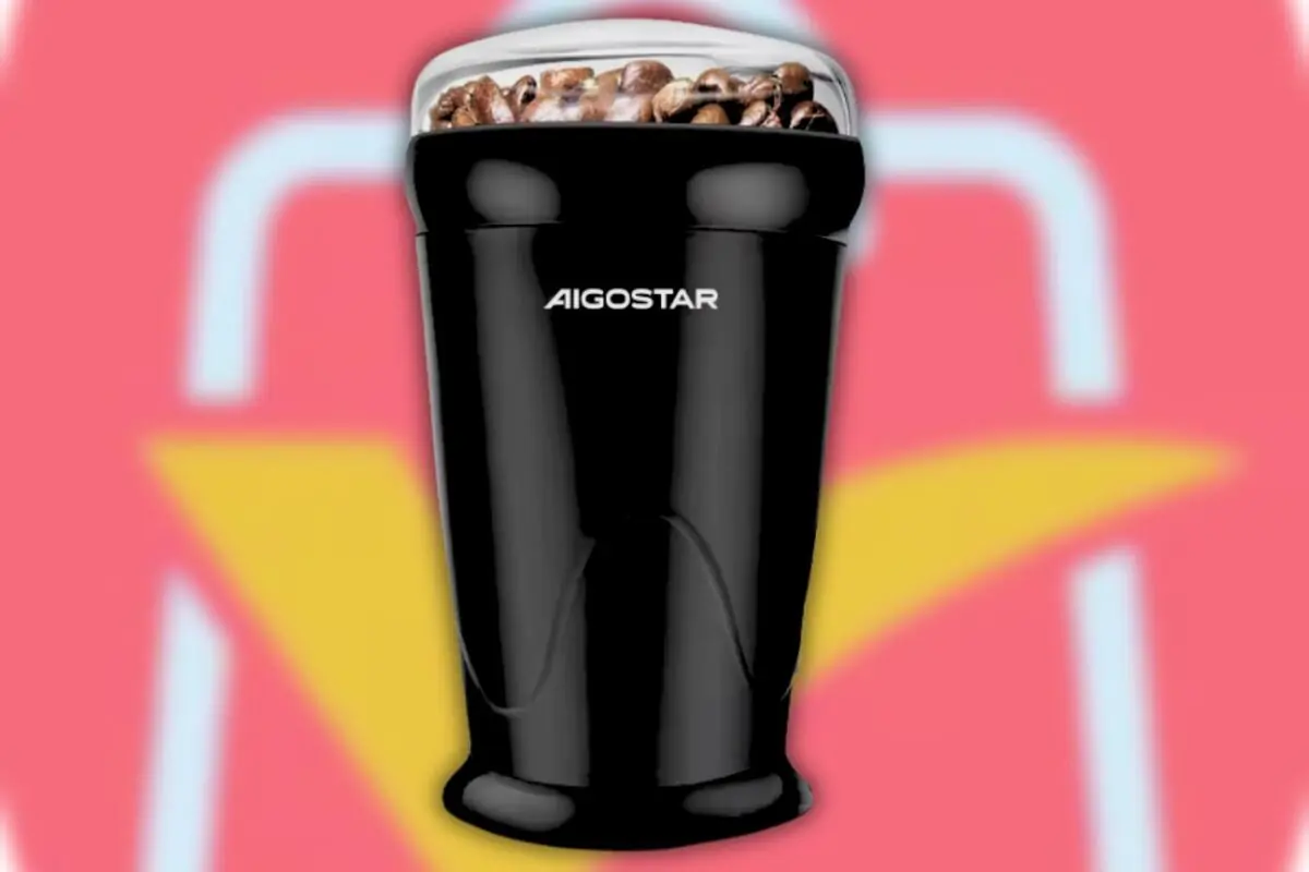 Molinillo eléctrico de café Aigostar negro con granos de café en el compartimento superior sobre fondo rojo y amarillo Molinillo eléctrico de café Aigostar negro con granos de café en el compartimento superior sobre fondo rojo y amarillo