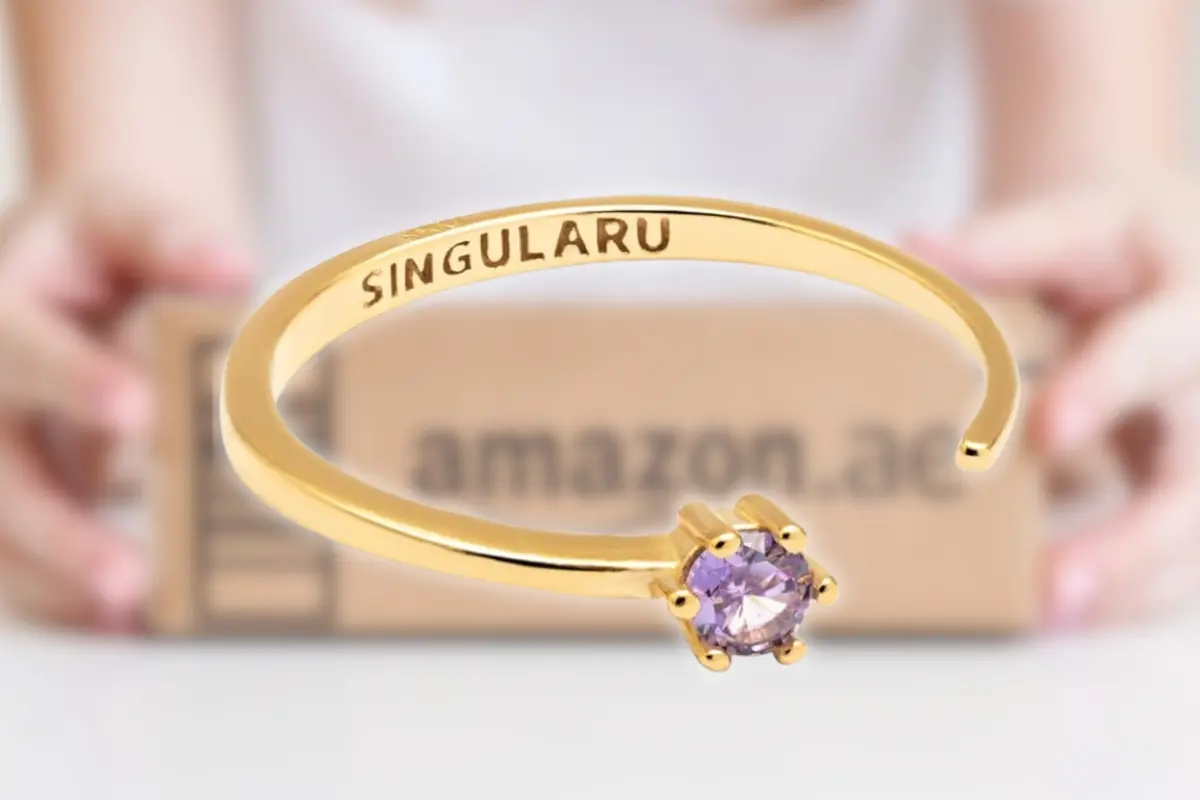 Montaje con anillo abierto dorado Singularu con piedra morada sobre fondo de caja de envío de Amazon