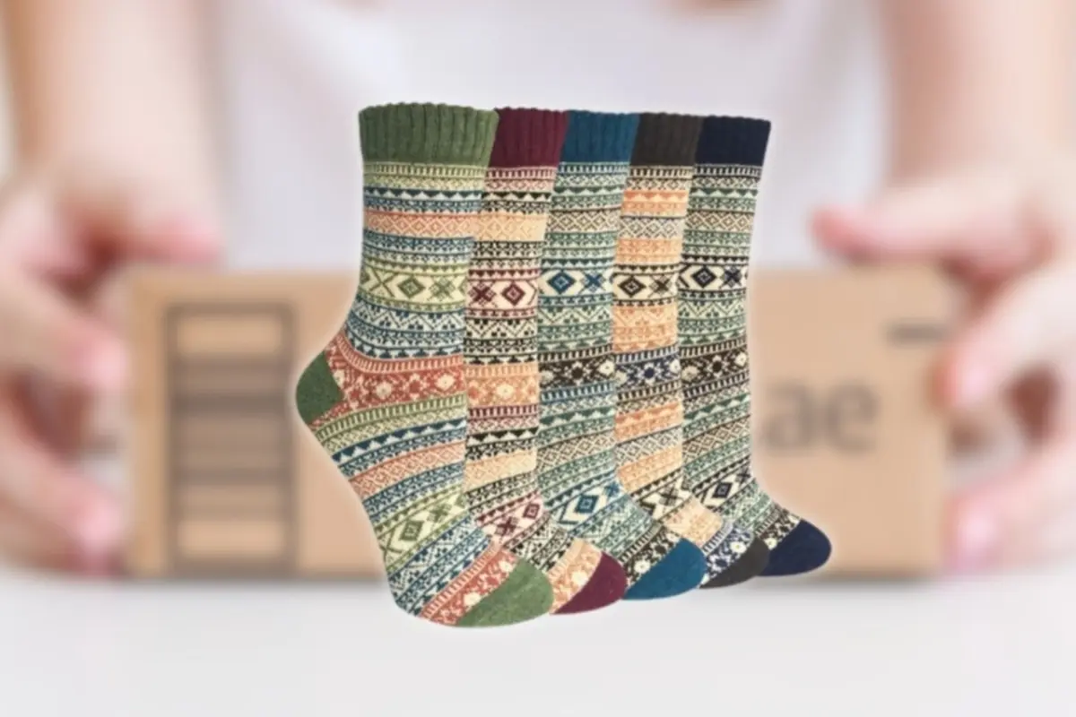 Cinco pares de calcetines de lana con estampado invernal multicolor frente a un paquete de cartón sostenido por una persona Cinco pares de calcetines de lana con estampado invernal multicolor frente a un paquete de cartón sostenido por una persona