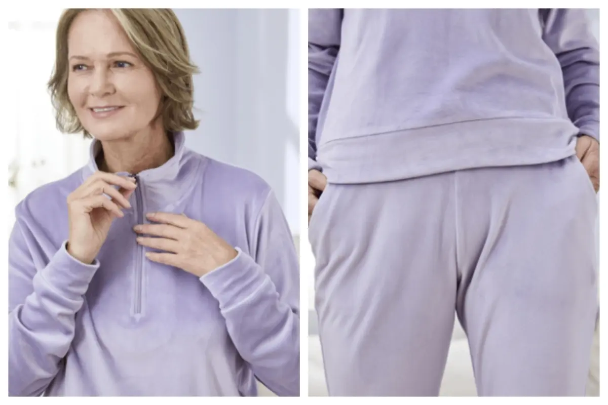 Una mujer sonriendo y luciendo un conjunto de chándal lila de terciopelo de Aldi con sudadera de media cremallera y pantalón a juego.