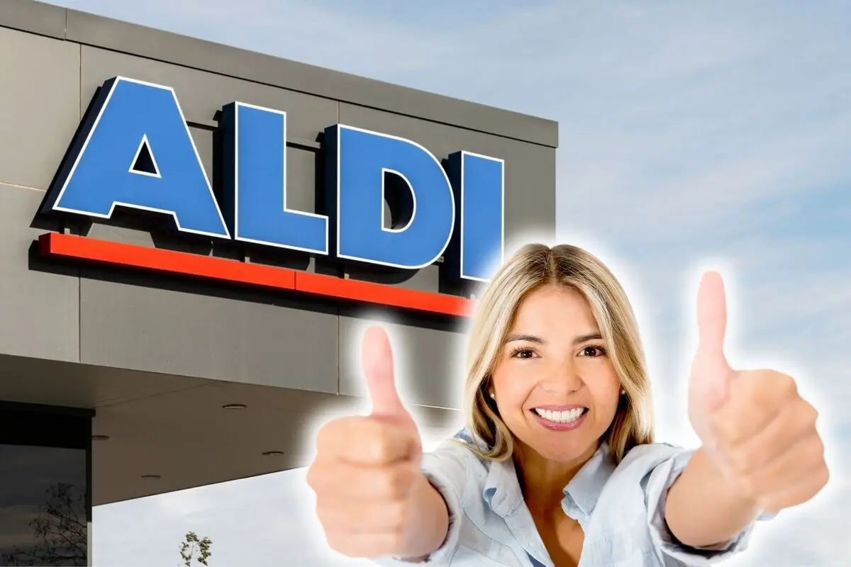 Mujer sonriente con ambos pulgares hacia arriba frente a la fachada de un supermercado ALDI.