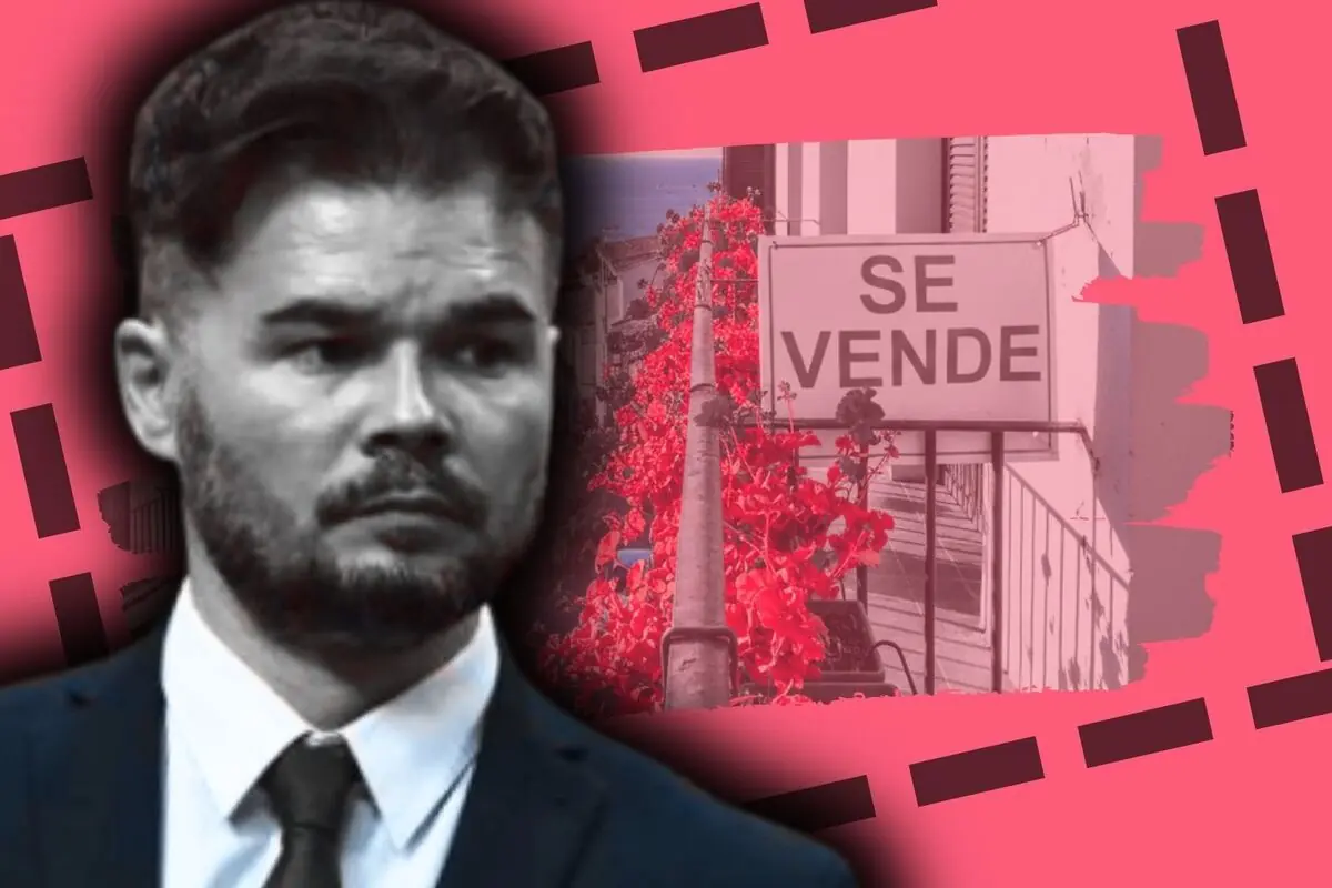 Gabriel Rufián en primer plano sobre fondo rosa junto a un cartel inmobiliario que dice 'SE VENDE' rodeado de flores rojas.