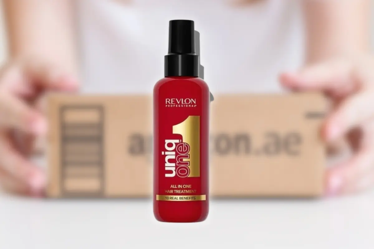 Montaje con botella roja de tratamiento capilar Revlon Uniq One en primer plano con una caja de envío de fondo desenfocado
