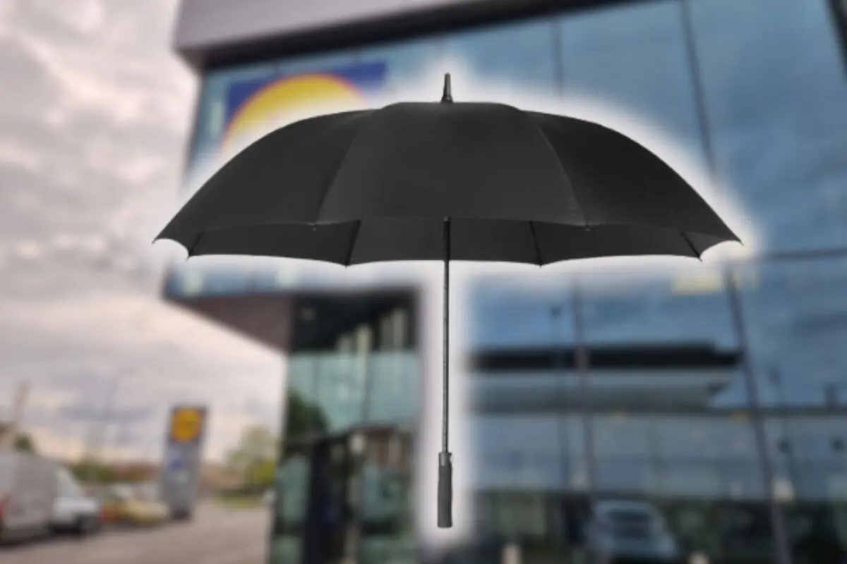 Paraguas negro abierto flotando frente a un edificio acristalado desenfocado