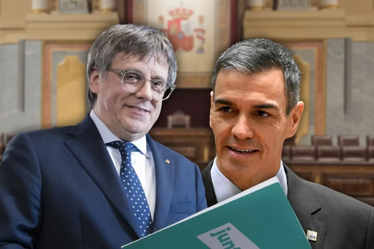 Dos polítics amb vestit somriuen i conversen a l’interior d’un parlament mentre un d’ells sosté una carpeta verda