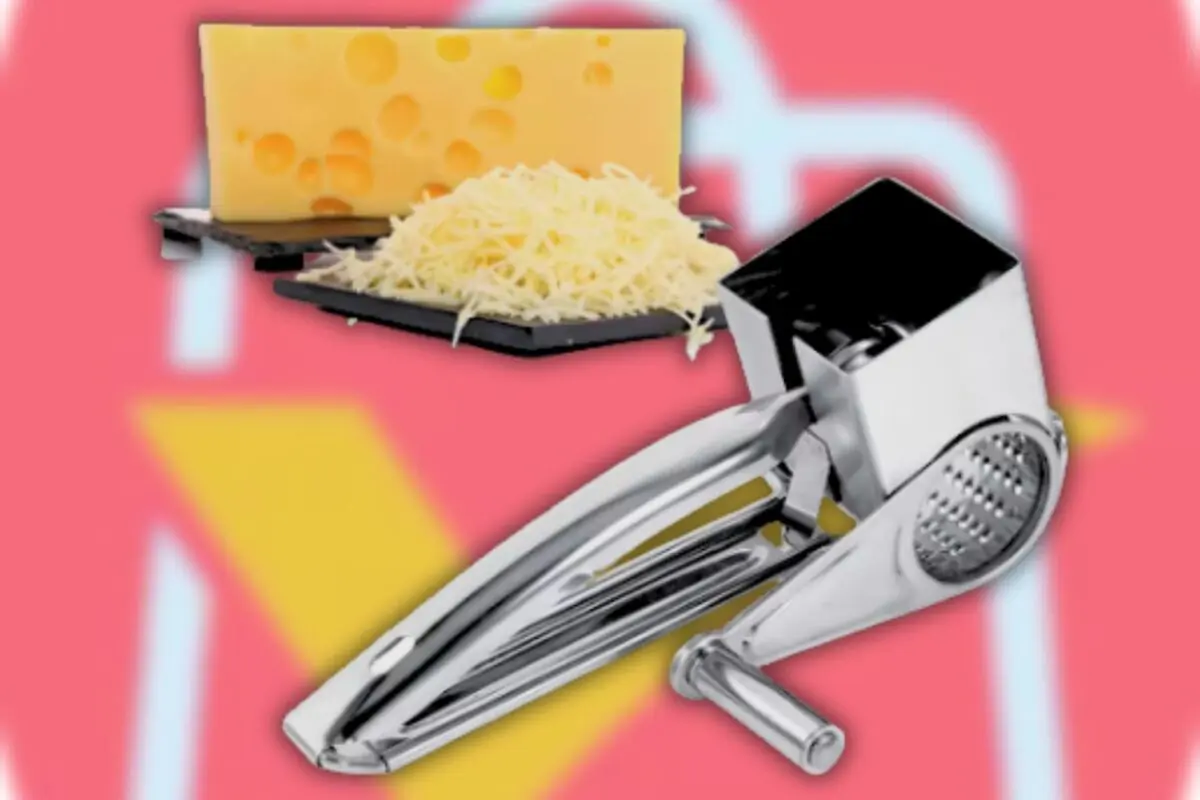 Rallador de queso metálico junto a un bloque de queso con agujeros y queso rallado sobre bandejas negras con fondo rosa