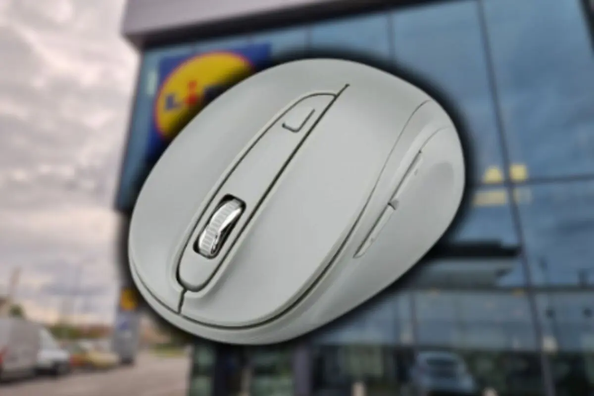 Ratón inalámbrico gris en primer plano con un edificio acristalado y un cartel de supermercado desenfocados al fondo