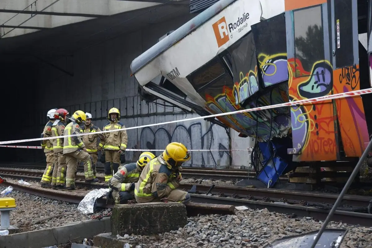Bomberos trabajando en las vías junto a un tren descarrilado con grafitis en un túnel ferroviario