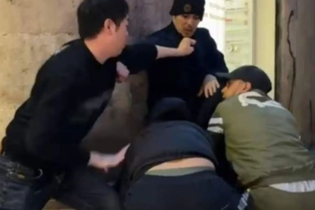 Quatre homes en una baralla de carrer al costat d’una paret, un dret llançant un cop de puny mentre un altre està acorralat i dos més s’ajupen a terra