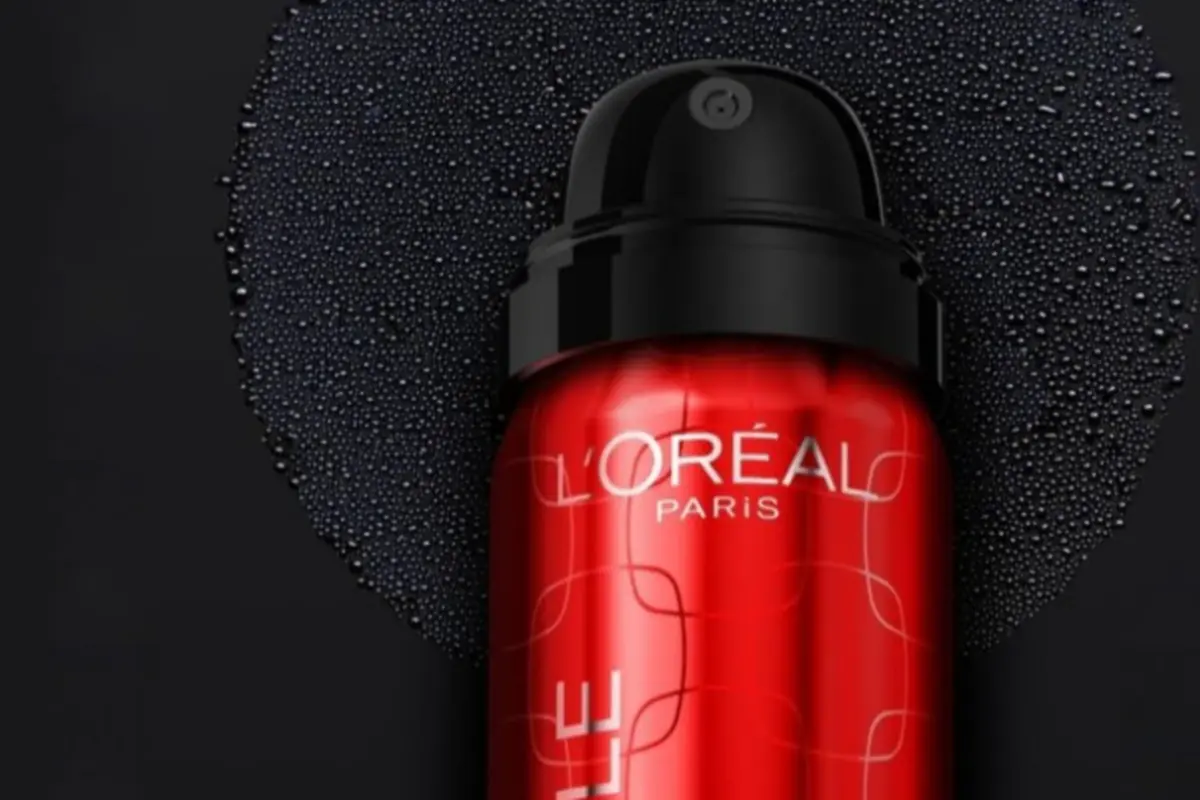 Envase rojo de espuma o gel L’Oréal Paris con tapa negra sobre fondo oscuro con gotas de agua Envase rojo de espuma o gel L’Oréal Paris con tapa negra sobre fondo oscuro con gotas de agua