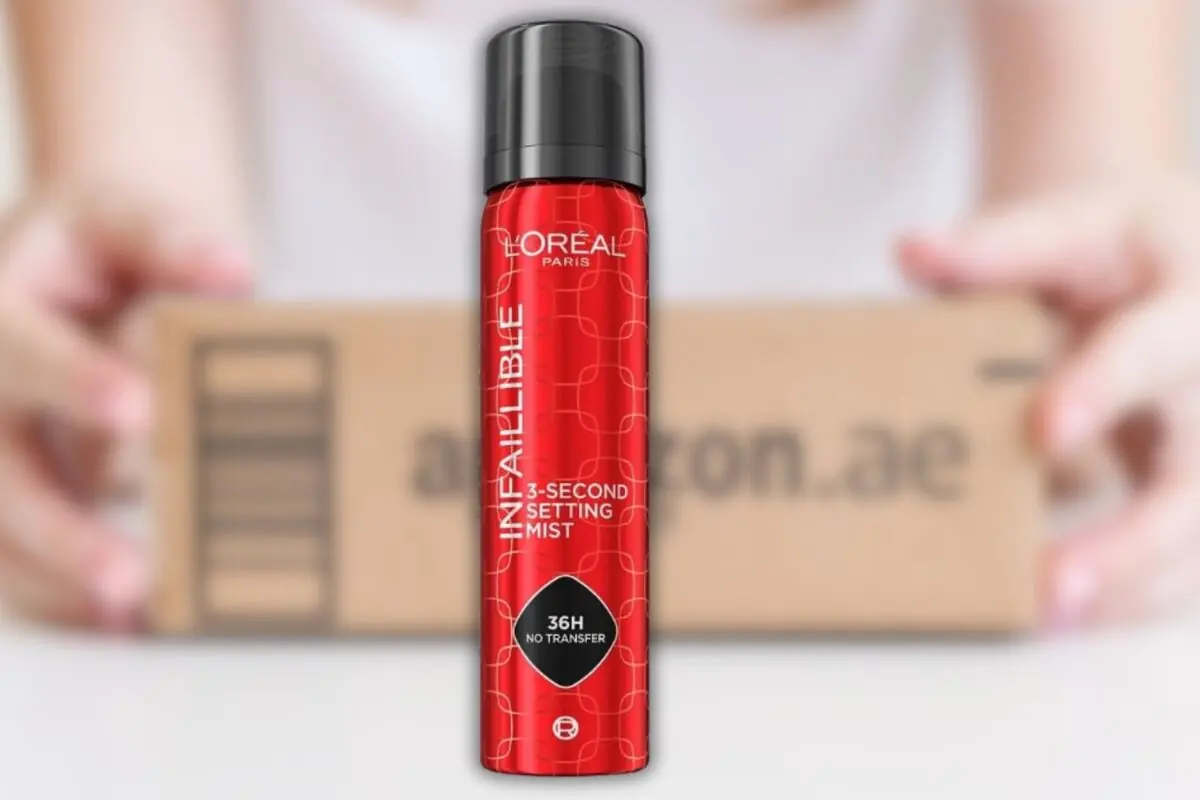 Spray fijador de maquillaje L’Oréal Paris Infallible en envase rojo frente a una caja de envío de Amazon desenfocada Spray fijador de maquillaje L’Oréal Paris Infallible en envase rojo frente a una caja de envío de Amazon desenfocada