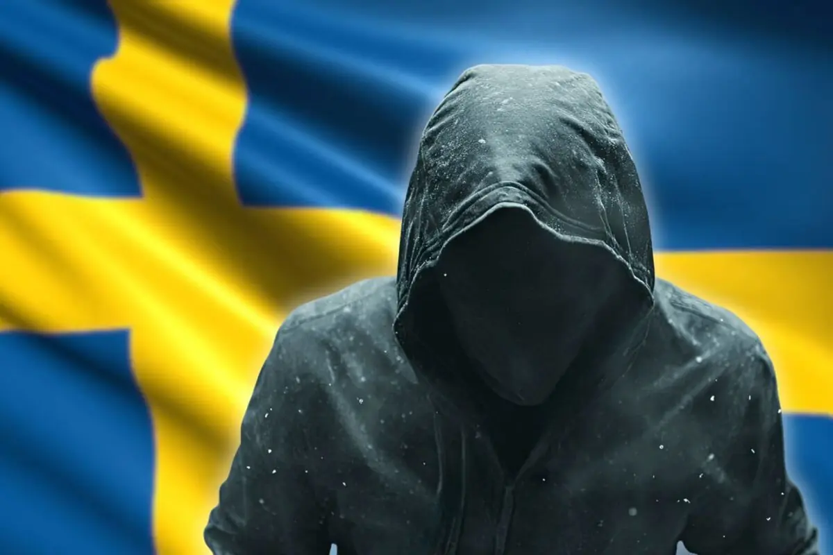 Silueta de persona encapuchada con rostro oculto frente a una gran bandera de Suecia ondeando
