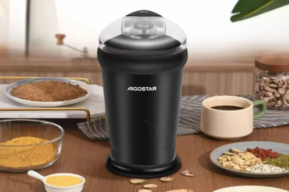 Molinillo eléctrico de café Aigostar negro sobre una mesa de cocina rodeado de tazas de café especias y granos Molinillo eléctrico de café Aigostar negro sobre una mesa de cocina rodeado de tazas de café especias y granos