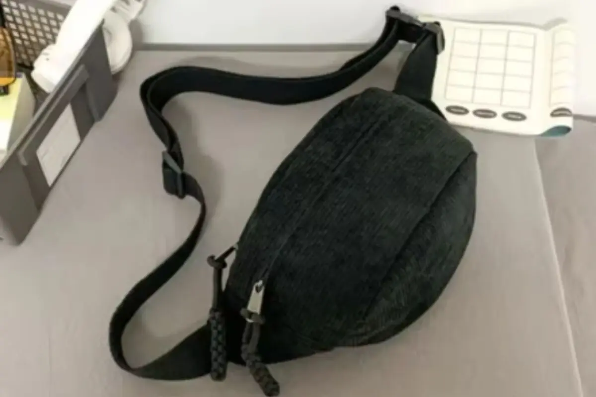 Riñonera negra de tela con correa ajustable apoyada sobre una superficie gris