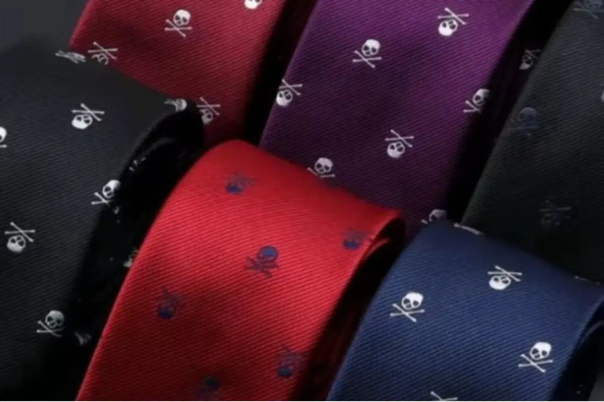 Corbatas de colores oscuros y rojo con estampado repetido de calaveras y huesos cruzados